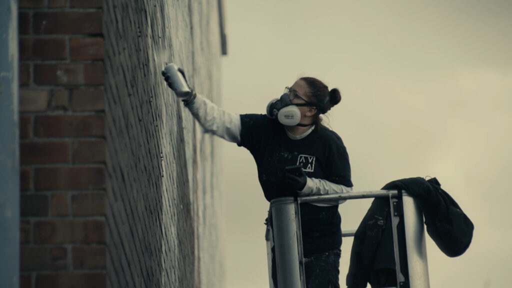 Artist painting wall wearing mask