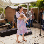 Woman holding a baby standing at a microphone