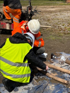 Student wearing high vis vest helps specialist site investigation team member